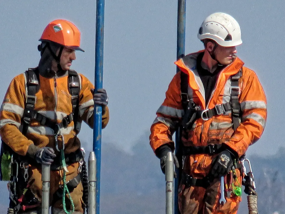 Two technicians in certified protective equipment and fall arrest harnesses