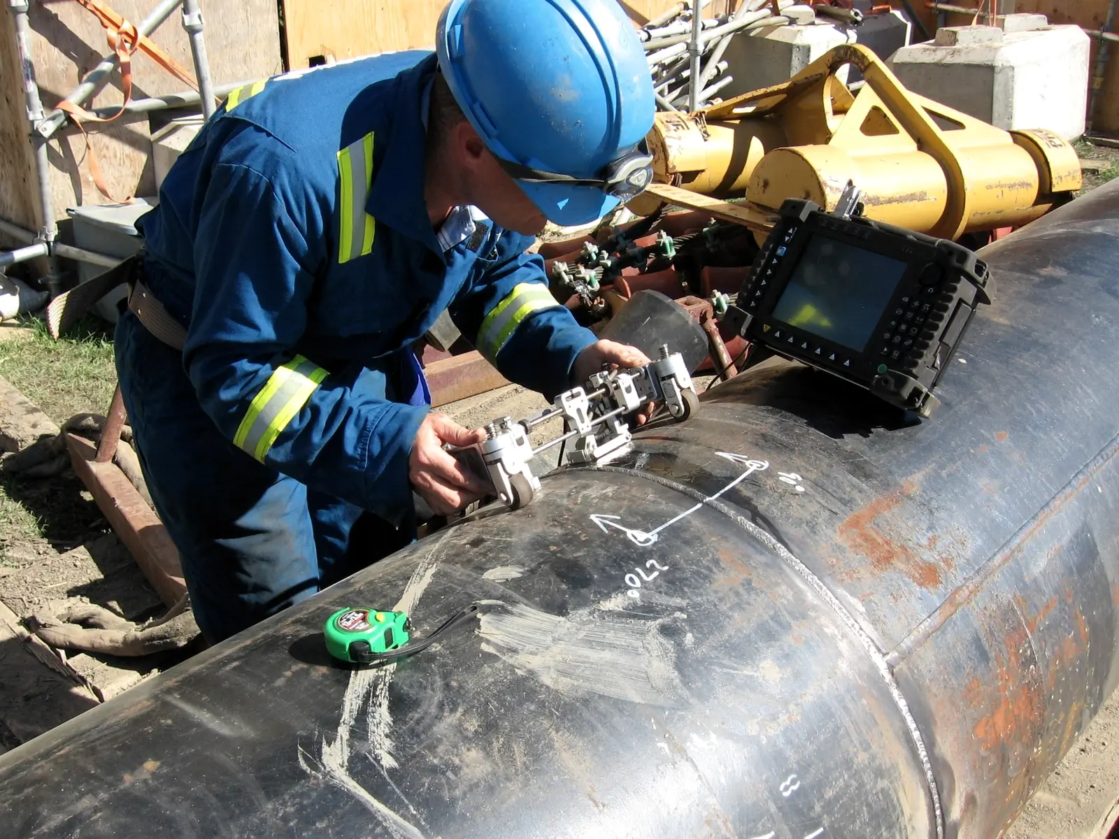 Inspector running an ultrasonic test along a welded pipeline joint