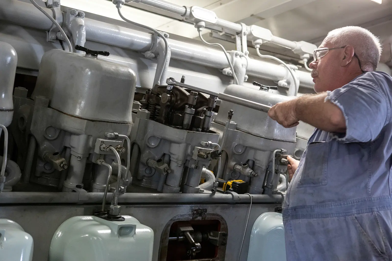 Technician working on a large diesel engine during a maintenance shift
