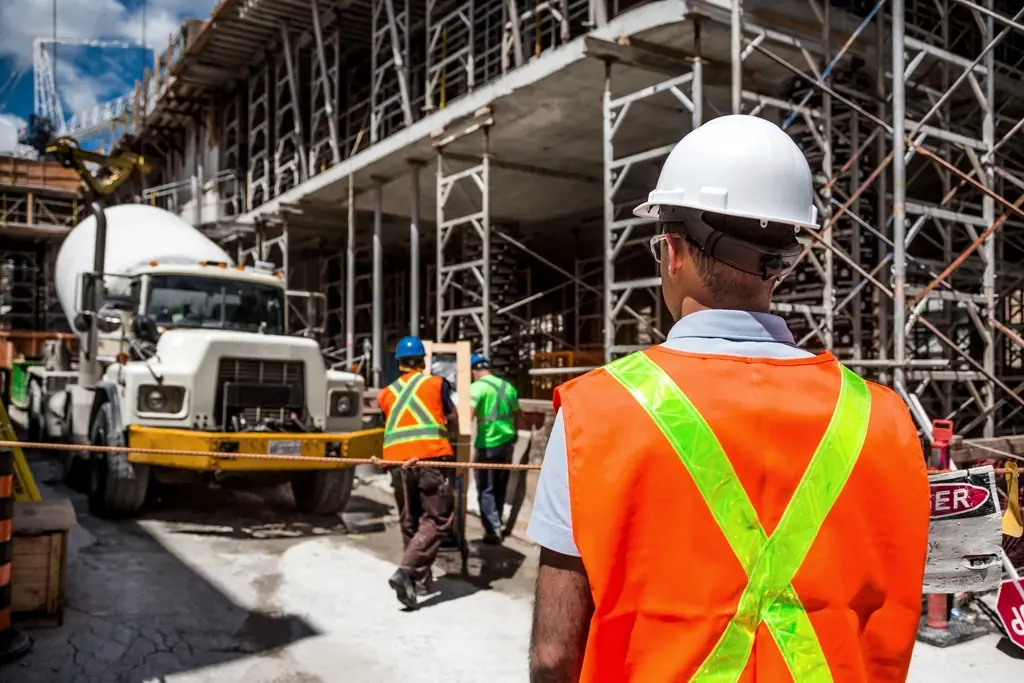 Site supervisor in a high visibility vest watching a concrete pour