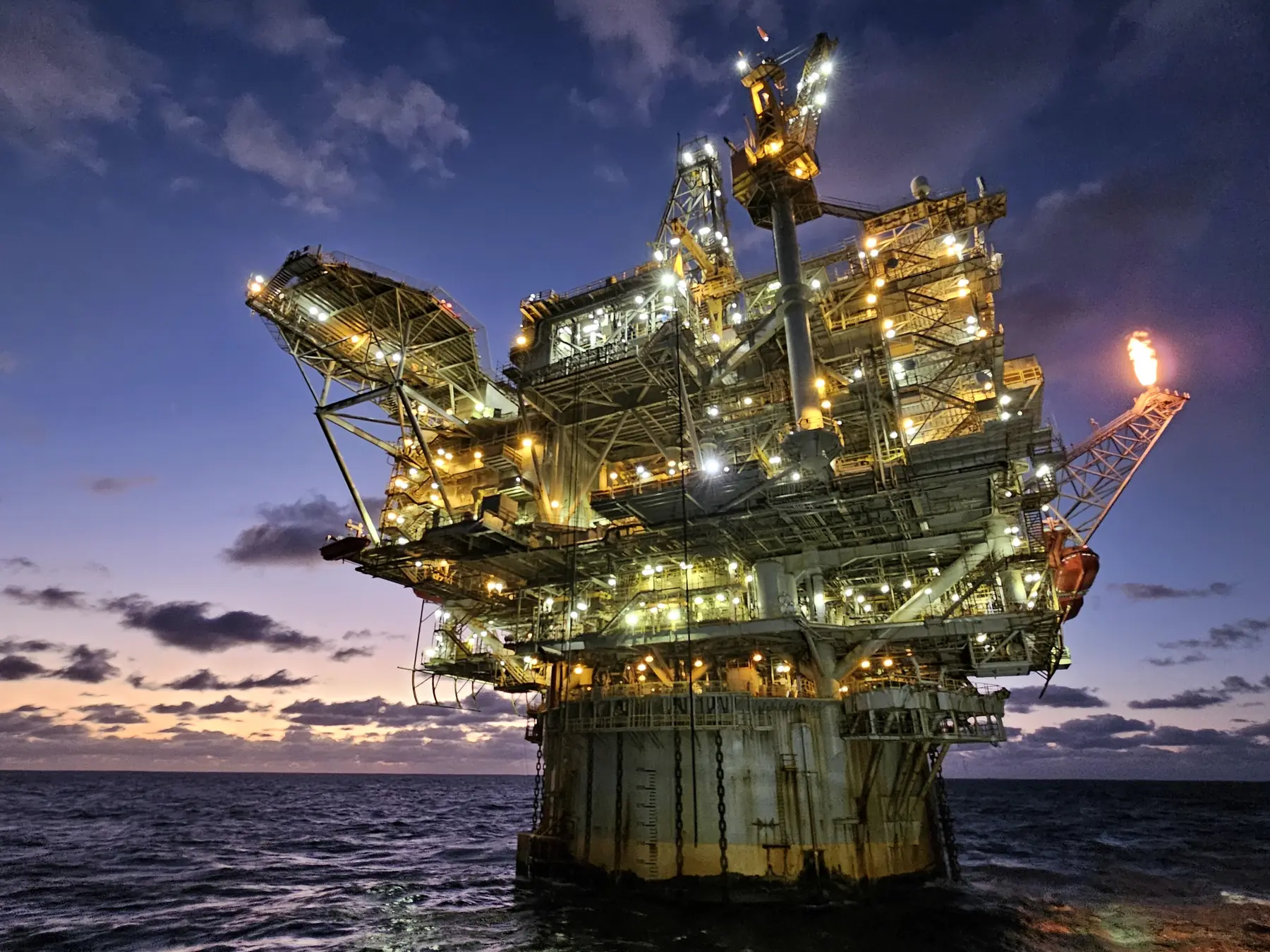 Offshore oil and gas production platform lit at dusk
