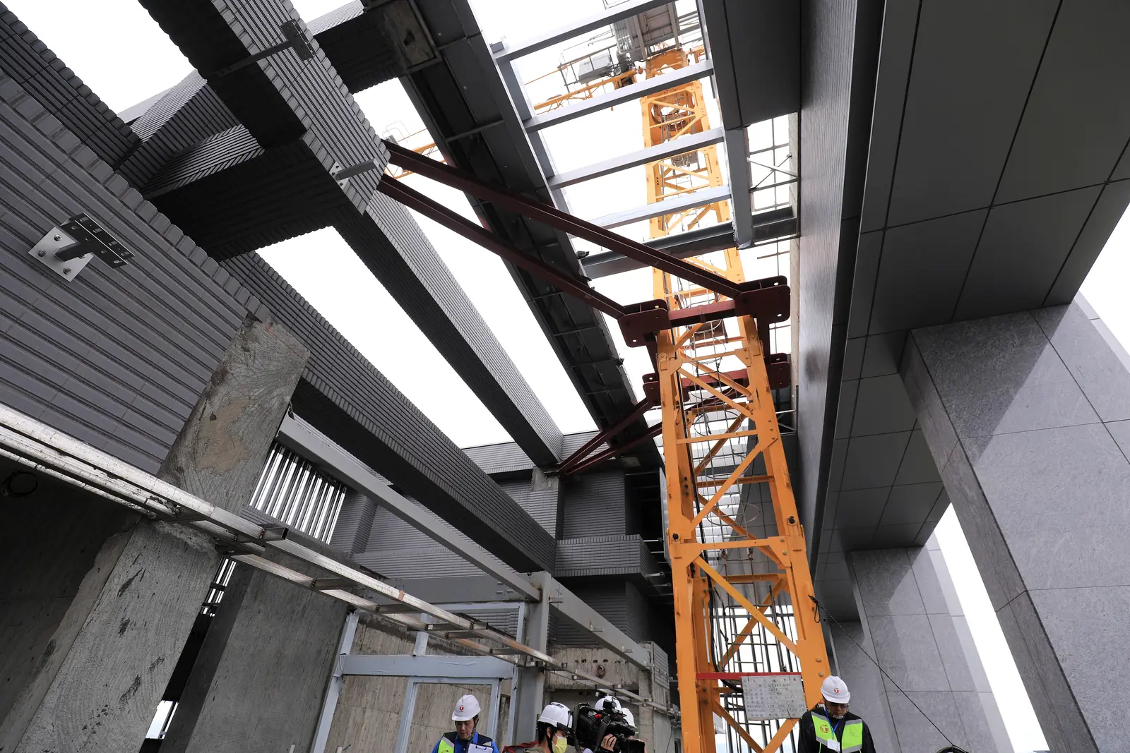 Engineers in hard hats beside a crane inside a building under construction